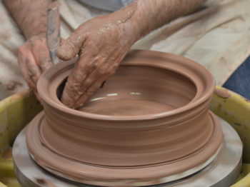 An artist works with a potter's wheel.