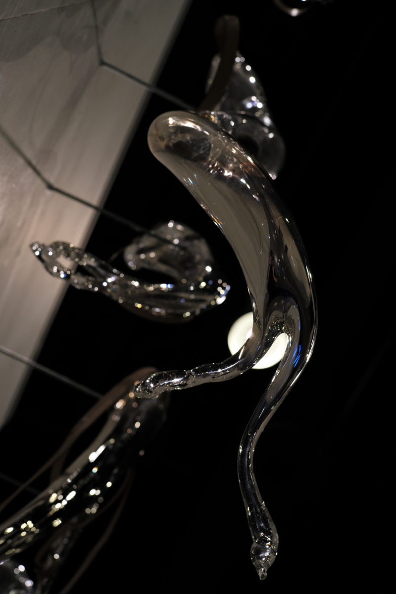 Close up of suspended clear sculpture that drips blood onto a lactic acid-treated paper below.