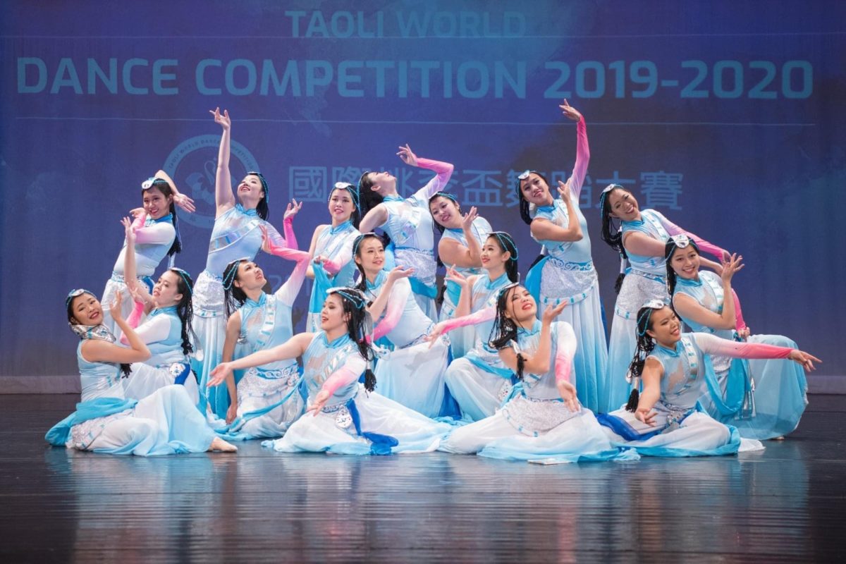 Group of dancers pose together on stage