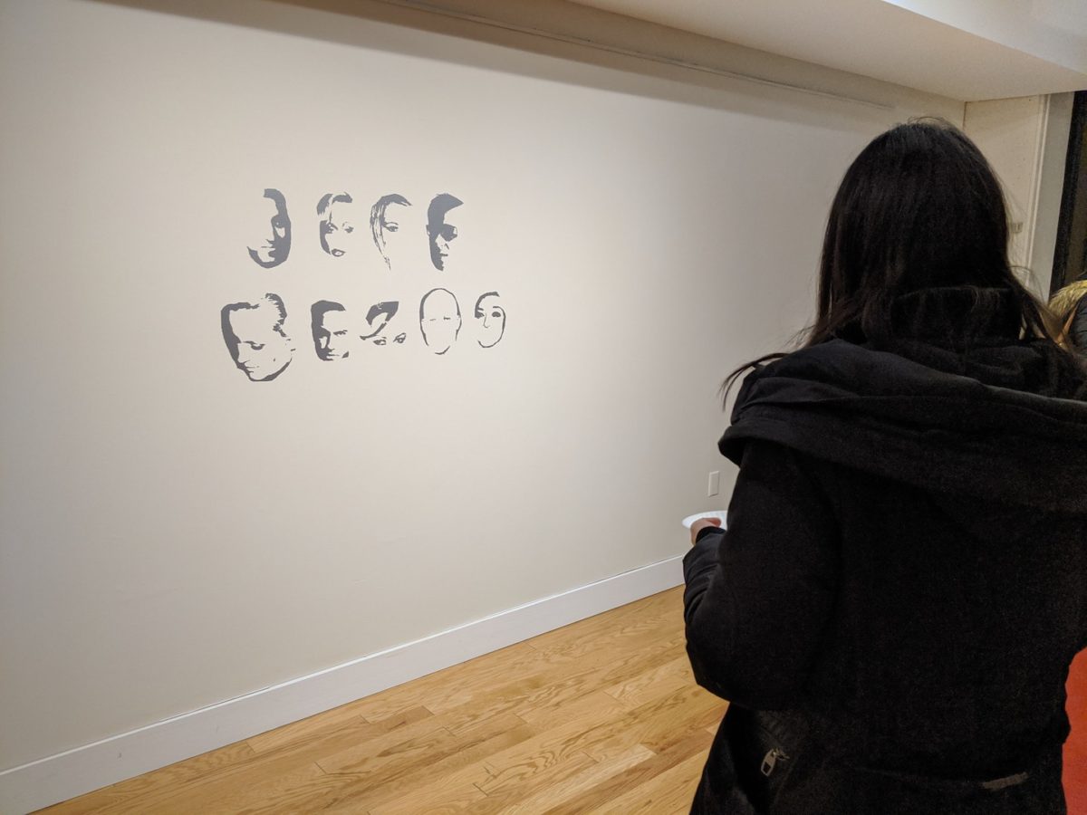 Installation view of Public Display as vinyl lettering on the wall. An onlooker, shown from behind, views the piece.