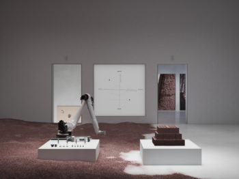 A gallery room with two low pedistals , one with a robotic arm and the other with ceramic bricks.