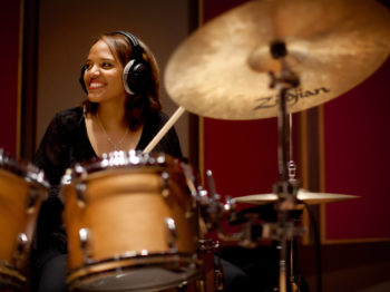 Terri Lyne Carrington smiles while playing on drums.