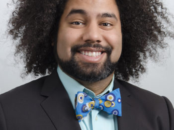 Daniel Chonde smiles directly at the camera while wearing a colorful bowtie and suit jacket.