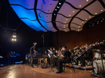 Fred Harris conducts the MIT Festival Jazz Ensemble on the MIT Kresge Auditorium stage.