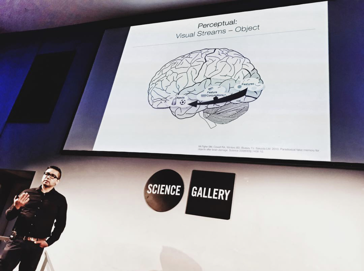 Man presents in front of a screen with an image of the brain