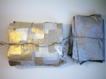 Two piles of metallic fabrics tied with threads.