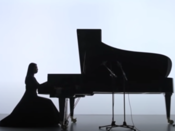 Silhouette of pianist Maki Namekawa's on the piano against a white screen.