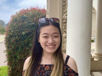 caroline smiles for the camera in front of columns