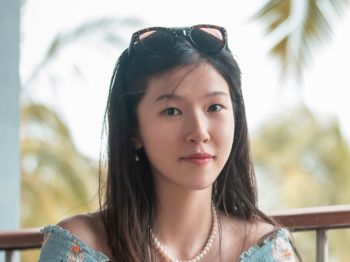 Yiming in a blue floral top poses outdoors