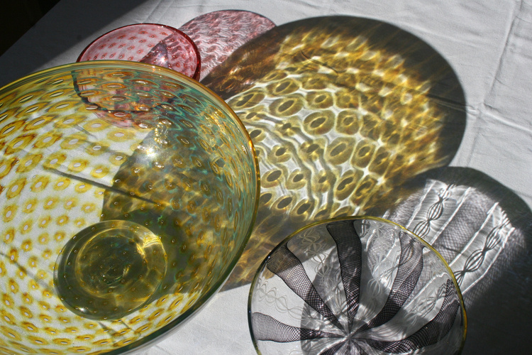 Glass bowls throw colorful shadows on a white surface