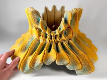 A crown-shaped sculpture made of yellow and green sand.