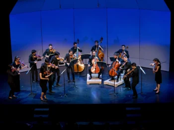 Orchestra playing at a stage with violet light setting.