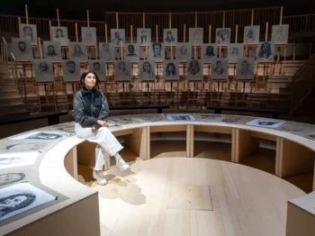 Artist and designer Es Devlin sits surrounded by drawings displayed on aisles. Credit: HErickson/MIT.