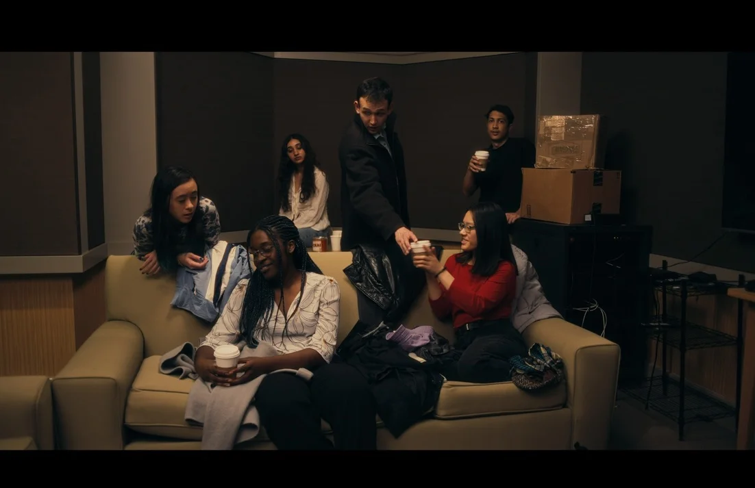 A group of students drink coffee together around a sofa