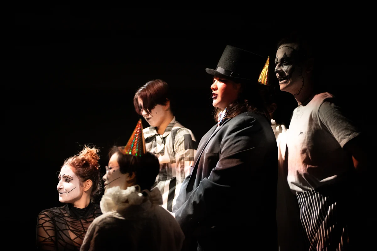 A group of theater performers in white face make up and hats.