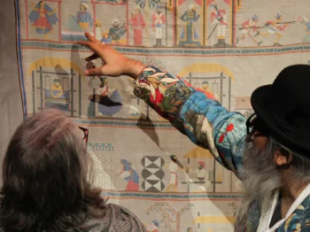Two people in front of a piece showing small different symbols