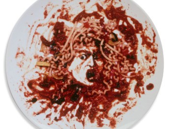 A portrait of medusa made of pasta and tomato sauce on a plate.