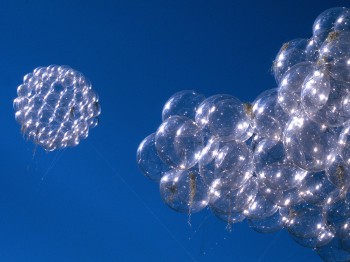 Clusters of clear orbs float in a blue sky.