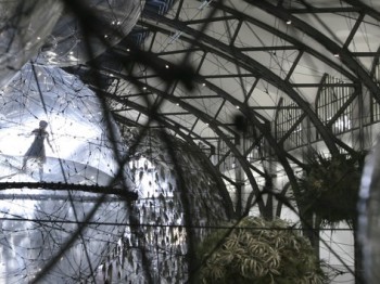 People walk inside large inflated globes within a metal structure.