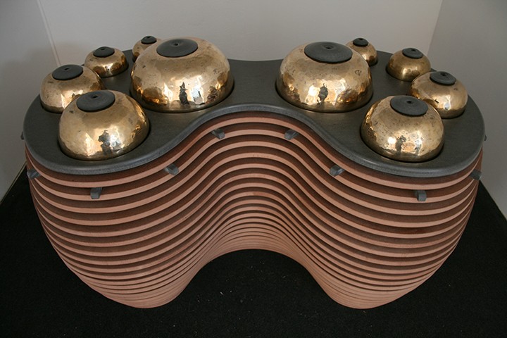 Ten coppery domes of various sizes on a table made of stacked wooden slats.