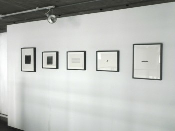 Five framed abstract black and white drawings on a gallery wall