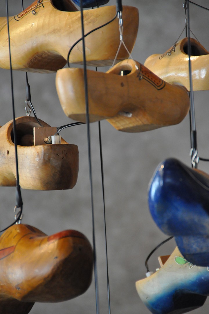 Wooden clogs hanging on wires.